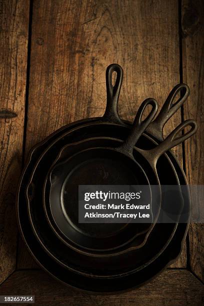 empty cast iron pans on wooden board - hierro fundido fotografías e imágenes de stock