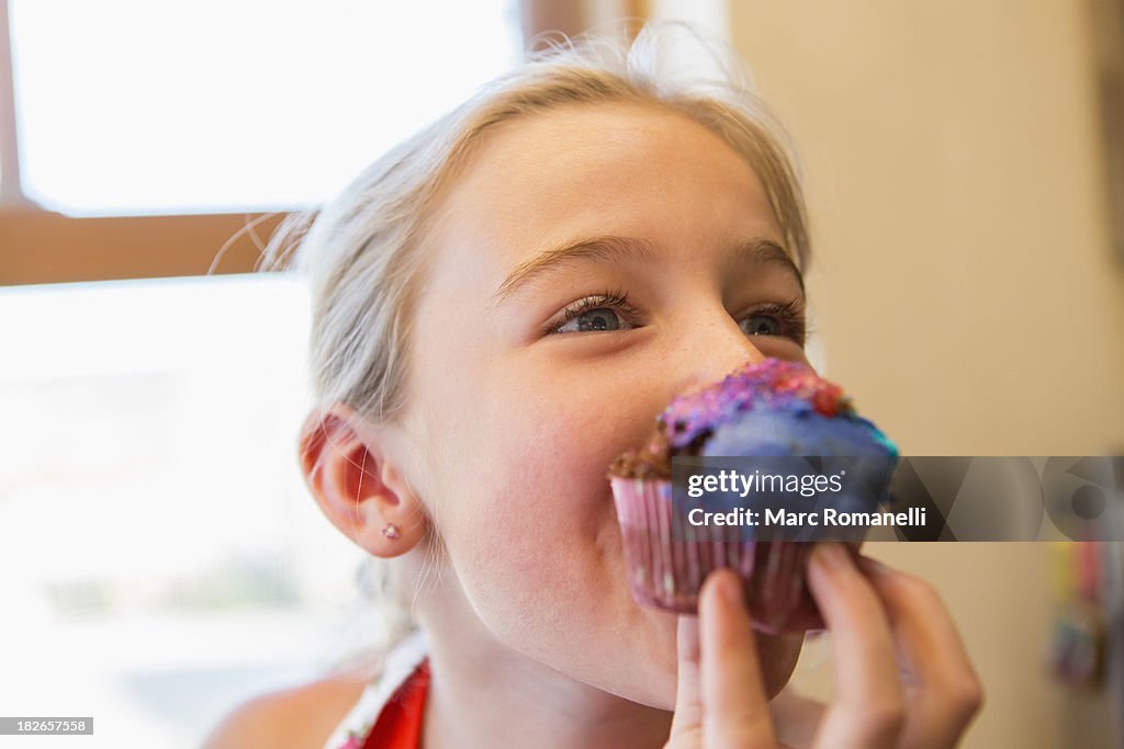 Caucasian girl eating cupcake