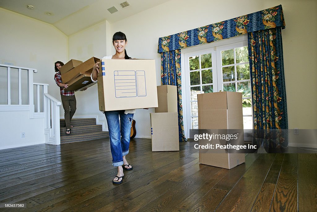 Couple carrying boxes in new home