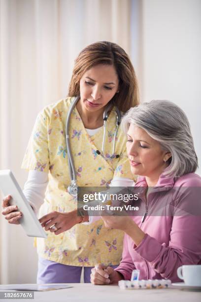 woman and caretaker discussing medications - client carer stock-fotos und bilder