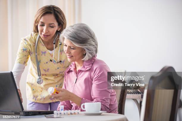 woman and caretaker discussing medications - client carer stock-fotos und bilder