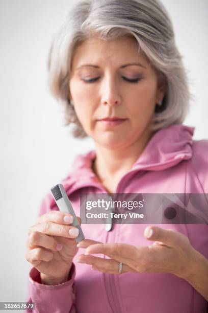 caucasian woman checking her blood sugar - blood sugar test stock pictures, royalty-free photos & images