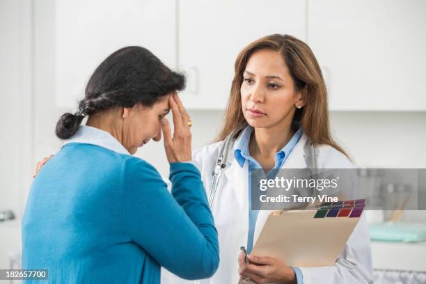 middle eastern doctor examining patient in office - arab old woman stock-fotos und bilder