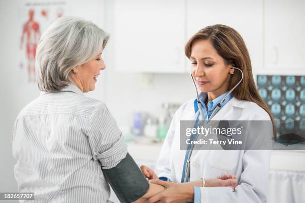 doctor examining patient in office - blood pressure stock-fotos und bilder