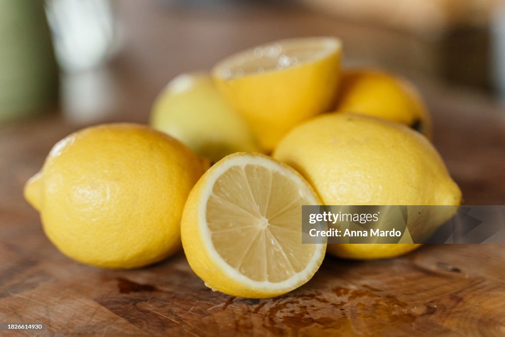 Half cut lemon on a wooden cutting board with lemons