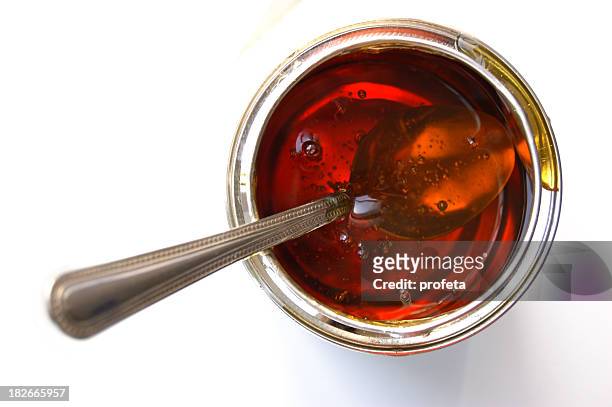 isolated image of a spoon inside a jar of syrup - syrup stockfoto's en -beelden