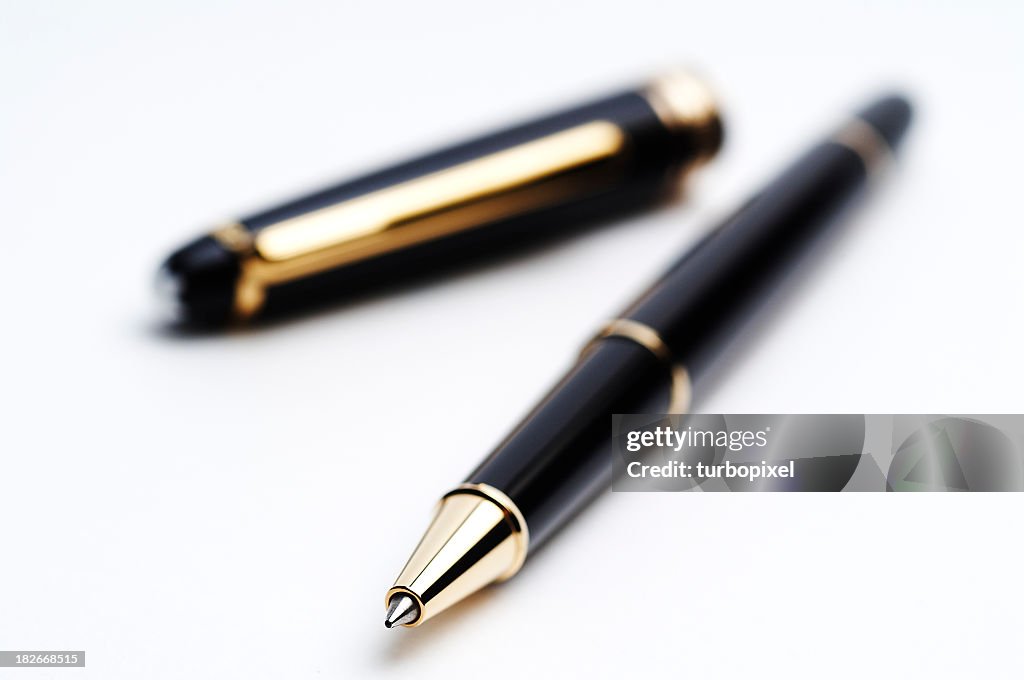 Black and gold ballpoint pen with cap on white background