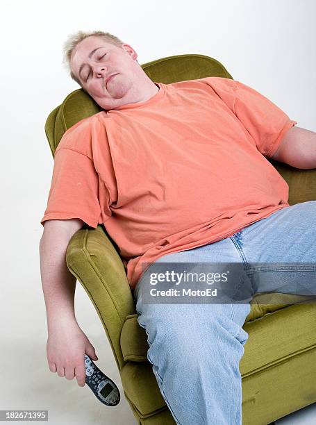 an obese man in orange shirt sleeping while holding a phone - fat man sitting stock pictures, royalty-free photos & images