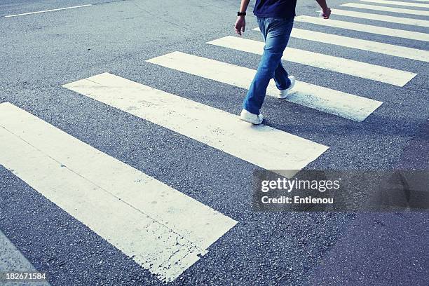 man in jeans walking across a zebra crossing - crosswalk stock pictures, royalty-free photos & images