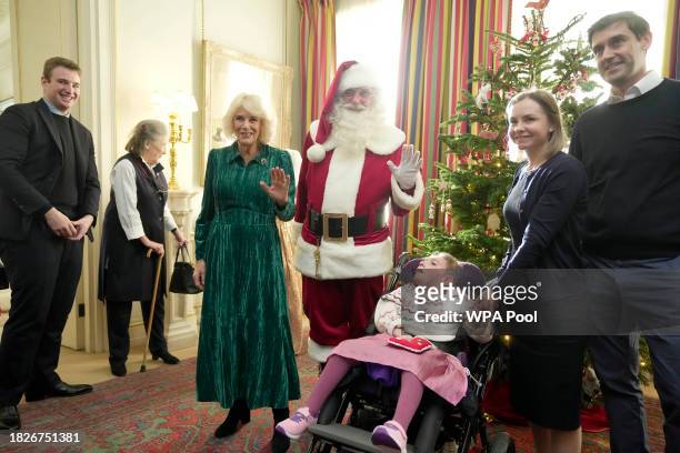 Britain's Queen Camilla poses with a man dressed as Father Christmas as she invited children, supported by Helen & Douglas House and Roald Dahl's...