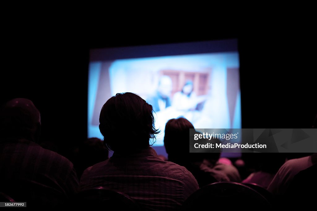 People watching movie in dark cinema