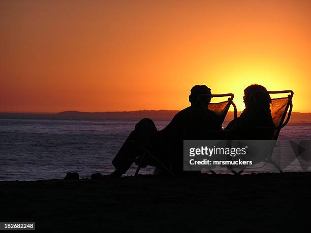 silhouette of elderly couple sitting in deckchairs on beach - early retirement stock pictures, royalty-free photos & images