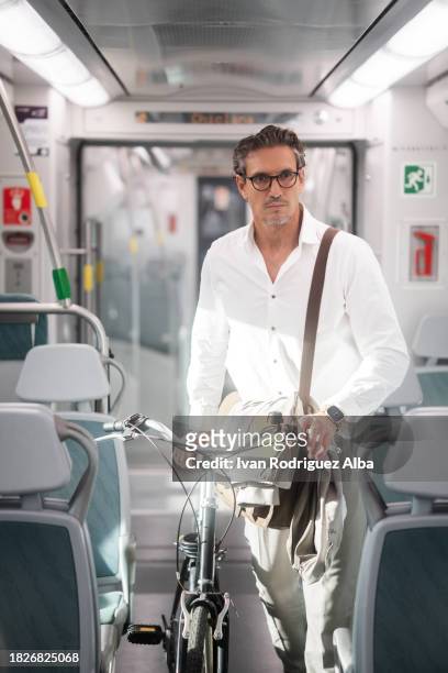businessman travelling by train holding a bicycle - passenger train stockfoto's en -beelden