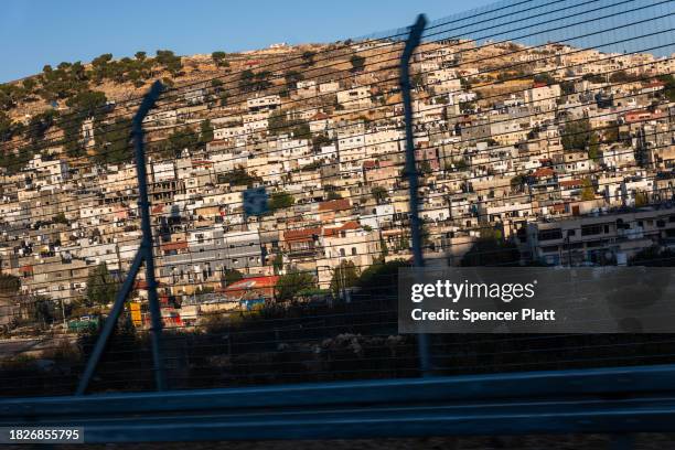 Israeli settlements sit behind a wire security fence along a road outside of Hebron during increased tensions between Palestinians and Israelis on...