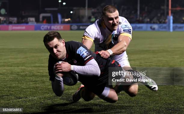 Tom Parton of Saracens dives over for their first try despite being held by Ollie Sleightholme during the Gallagher Premiership Rugby match between...