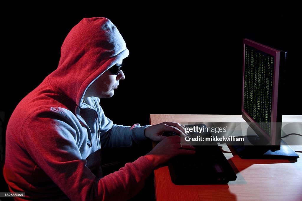 Hombre con gafas de sol hacks computadora en la noche