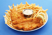 A close up of a fish and chips platter with dipping sauce