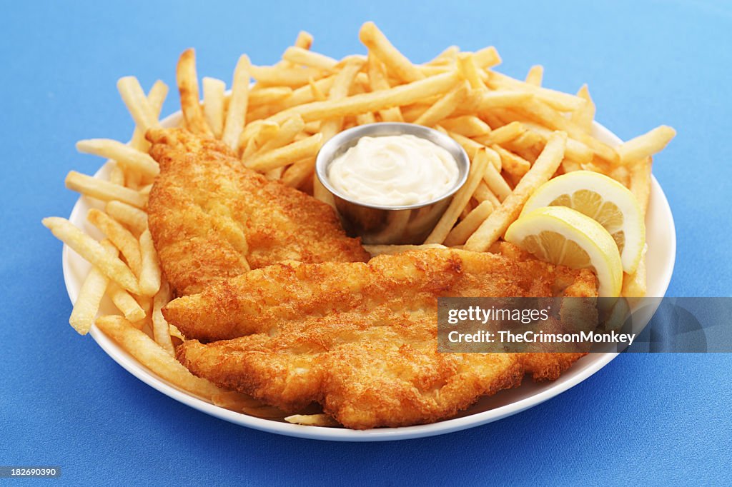 A close up of a fish and chips platter with dipping sauce