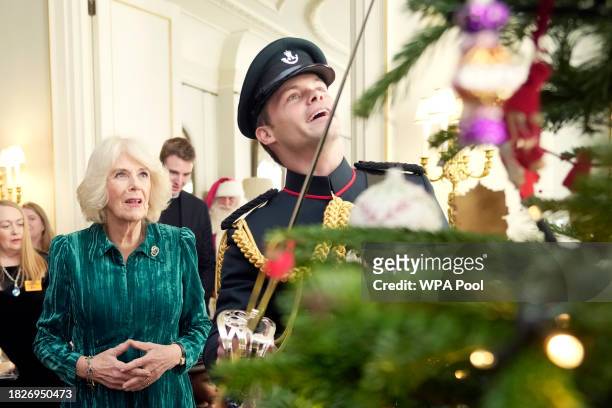 Britain's Queen Camilla looks at the Christmas tree after she invited children, supported by Helen & Douglas House and Roald Dahl's Marvellous...