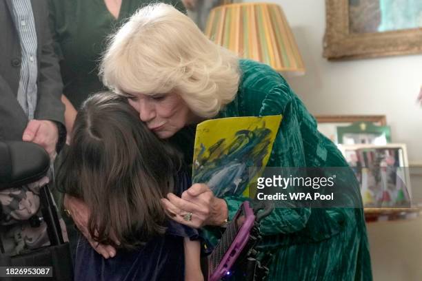 Britain's Queen Camilla hugs a child after she invited children, supported by Helen & Douglas House and Roald Dahl's Marvellous Children's Charity,...