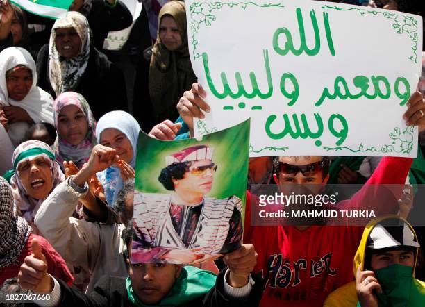 Holding up posters of their leader Moamer Kadhafi, some of the thousands of Libyans celebrate victories over rebel forces claimed by Moamer Kadhafi's...