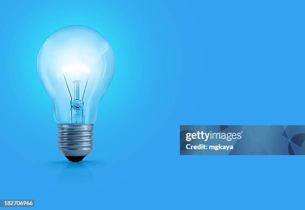 glühbirne auf blauem hintergrund - lightbulb stock-fotos und bilder