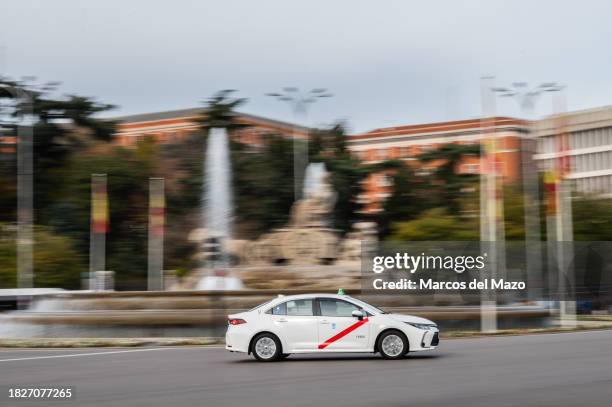 Taxi drives passing by Plaza de Cibeles, downtown Madrid.