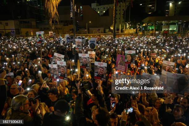 Thousands of people and the families of kidnapped Israelis hold up their mobile phones with the torch light to sing the national anthem during a...