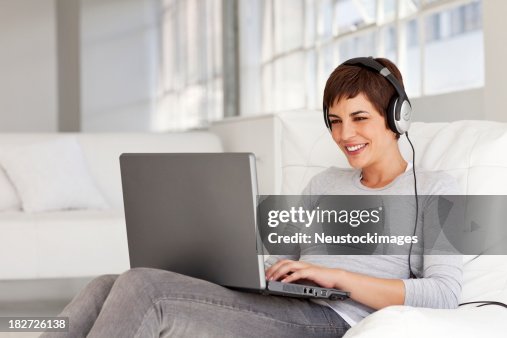 Young Woman Sitting on Chair Smiling Wearing Headphones Young Woman Sitting on Chair Smiling Wearing Headphones