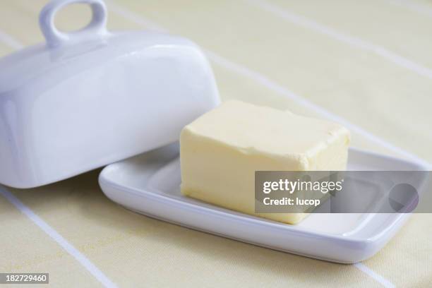 butter block on white ceramic butter container on yellow background - butter dish stock pictures, royalty-free photos & images