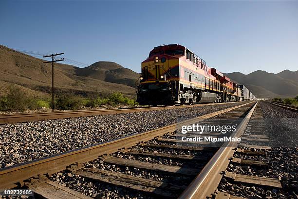 angled view of train tracks with oncoming freight train - tramway stockfoto's en -beelden