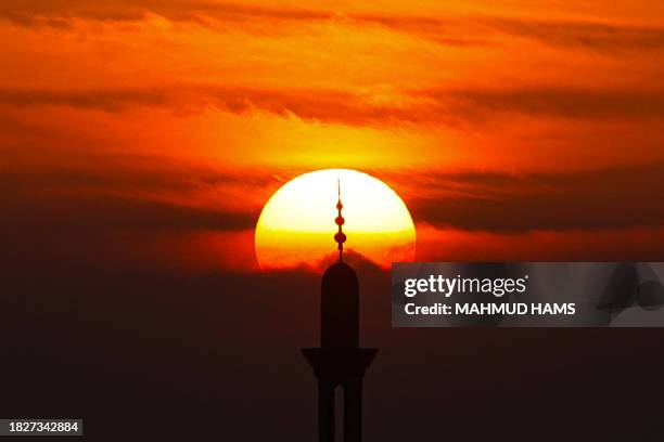 Picture taken from Rafah on the southern Gaza Strip on December 6 shows the minaret of a mosque silhouetted against the setting sun amid continuing...