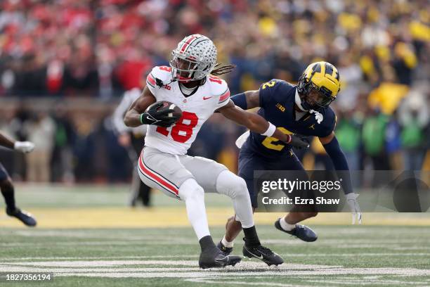 Marvin Harrison Jr. #18 of the Ohio State Buckeyes makes a catch against Will Johnson of the Michigan Wolverines during the third quarter in the game...