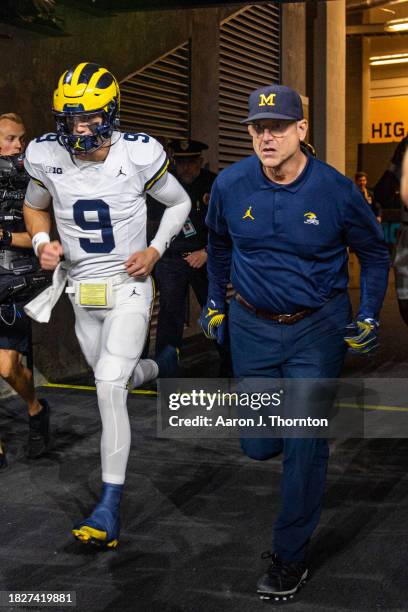 McCarthy and Head Football Coach Jim Harbaugh of the Michigan Wolverines are seen running onto the field before the Big Ten Championship against the...