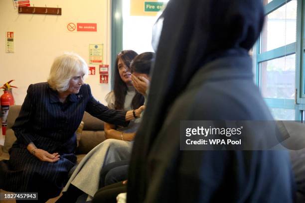 Queen Camilla comforts a crying former resident as she visits Ashiana women's refuge on December 6, 2023 in London, England.