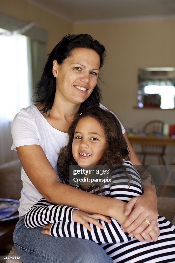 Mother with arms around her daughter indoors