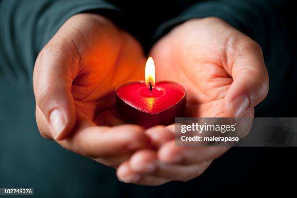 heart-shaped candle in her hands - kaarsen stockfoto's en -beelden