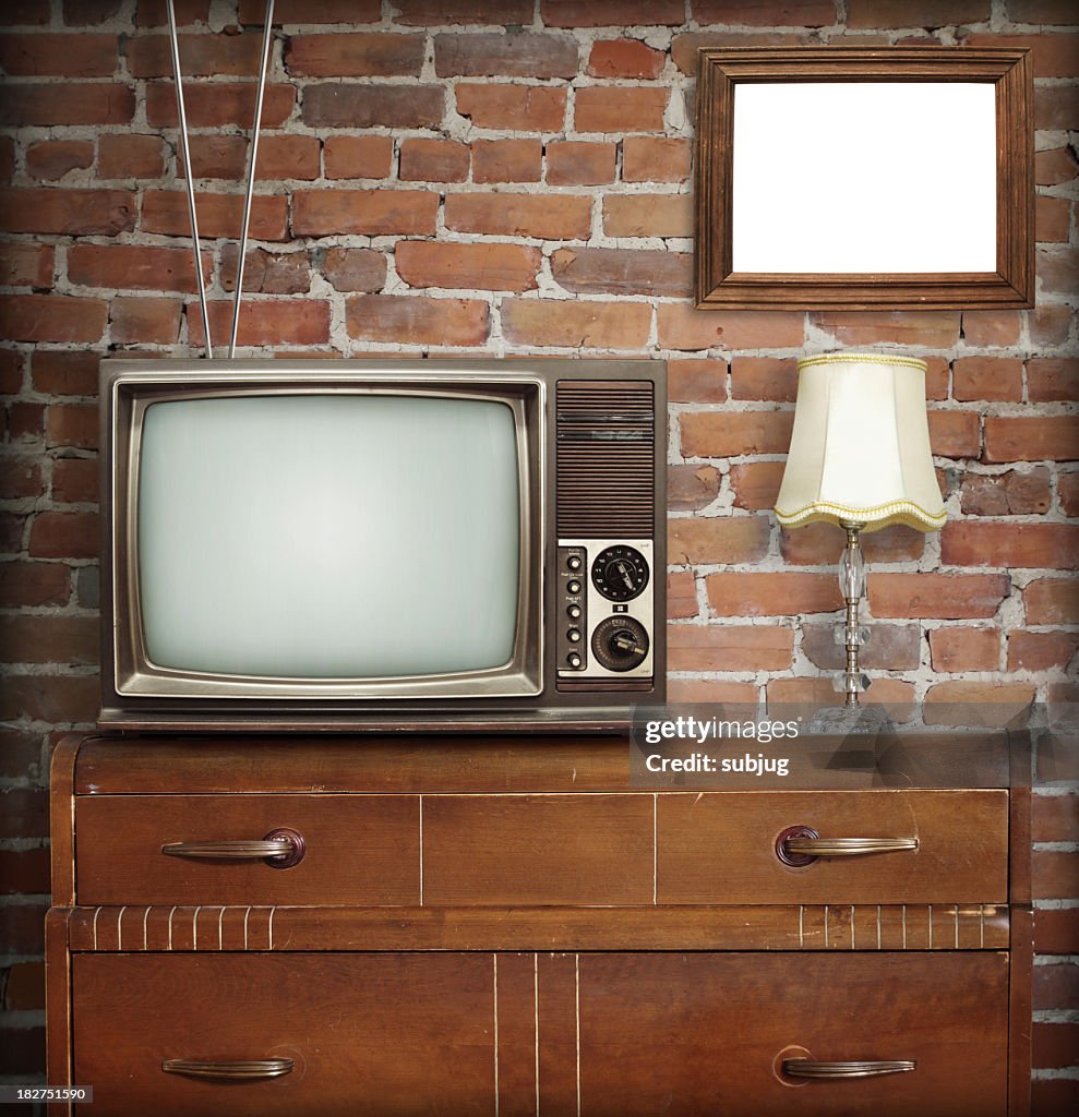 Antennae television sitting on dresser with antique lamp 