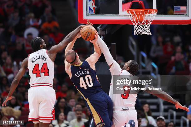 Patrick Williams and Andre Drummond of the Chicago Bulls block a shot by Cody Zeller of the New Orleans Pelicans during the first half at the United...