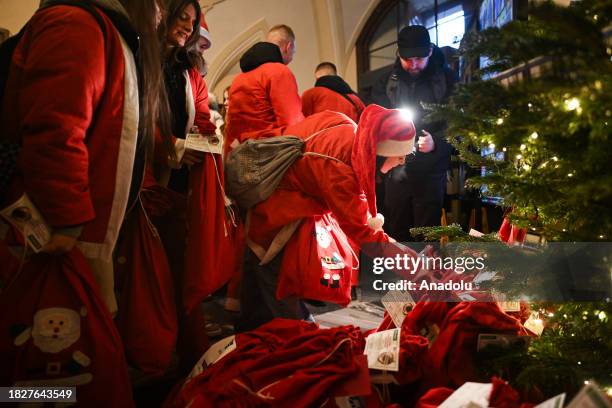 Teenagers, dressed as Santa Claus, place gift boxes under the tree as they take part in a parade on the Saint Nicholas Day in Krakow, Poland on...