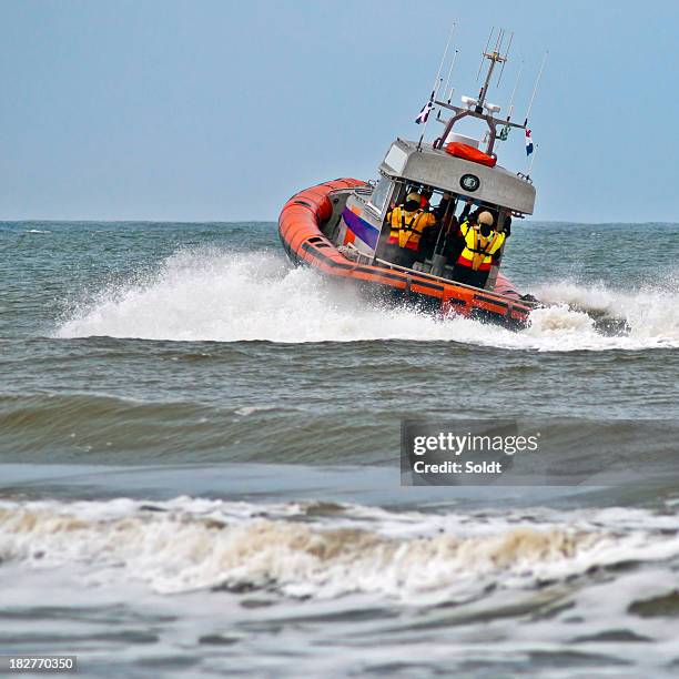 a lifeboat rides a wave as it sets off into action - coast guard stock pictures, royalty-free photos & images