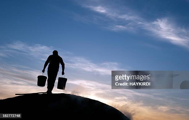 man is carrying water at rural area - bucket stock pictures, royalty-free photos & images