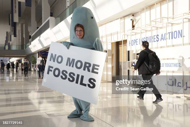 An environmental activist dressed as a dugong, a sea creature native to the United Arab Emirates, holds a sign that reads: "No More Fossils" in one...