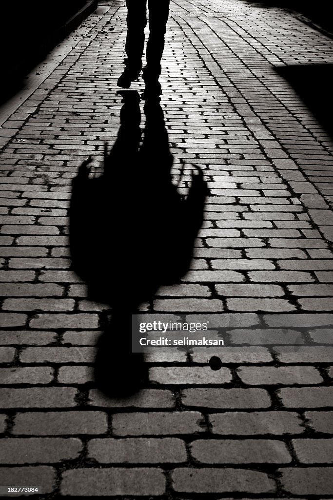 Black And White Shadow Of Man Walking On Sidewalk