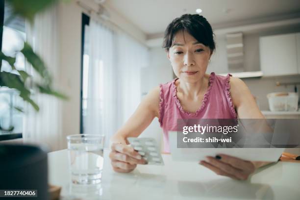 asian woman is carefully reviewing the patient information leaflet for her medication. - hormone stock pictures, royalty-free photos & images