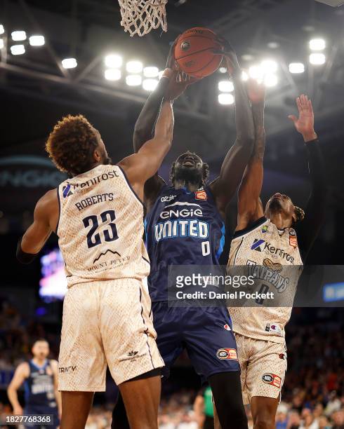 Jo Lual-Acuil Jr of United attempts to shoot under pressure from Josh Roberts of the Taipans and Tahjere McCall of the Taipans during the round nine...