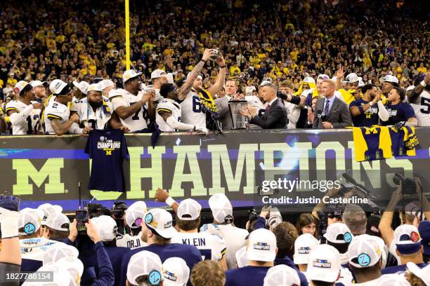 Zak Zinter of the Michigan Wolverines lifts the trophy after winning the Big Ten Championship \aii at Lucas Oil Stadium on December 02, 2023 in...