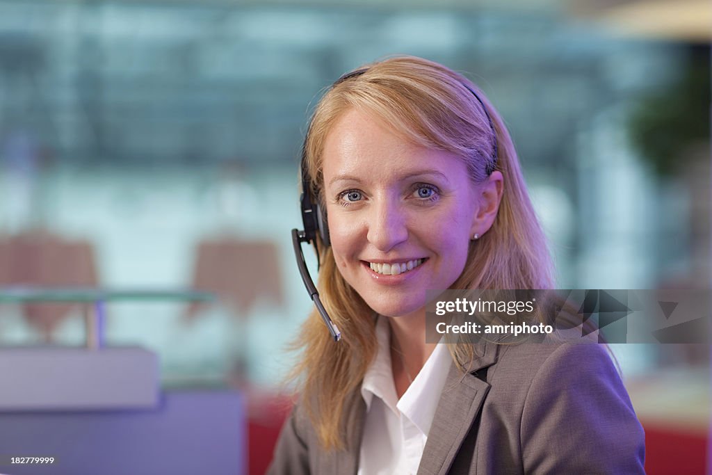 Friendly woman with headset at helpdesk