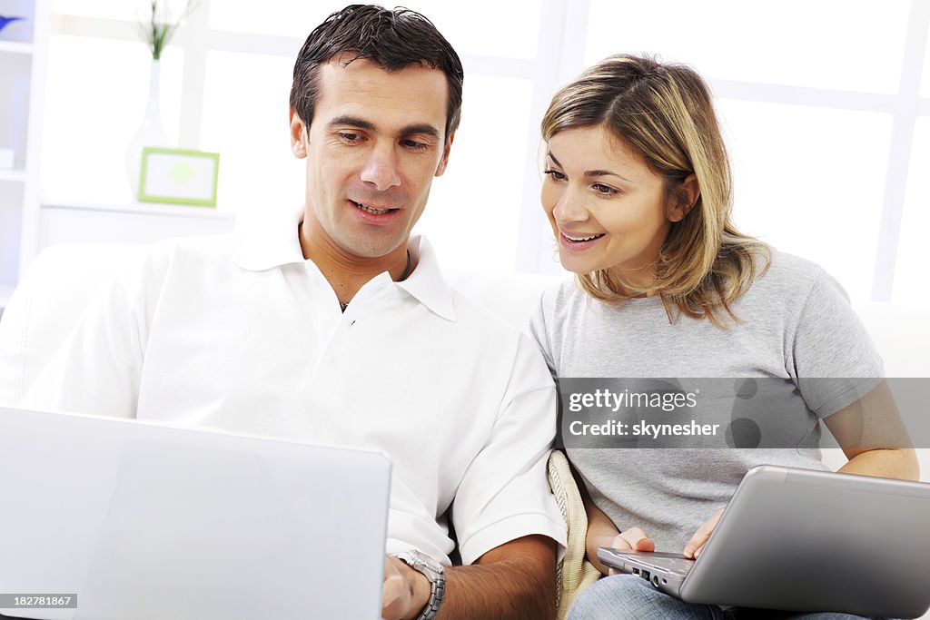 Couple using a laptop computer, sitting at home.
