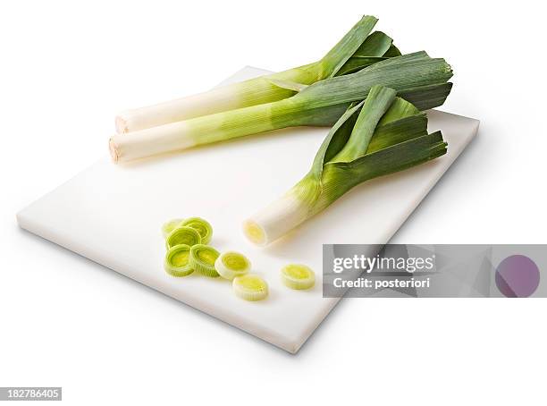 three leeks on a white cutting board - posteriori stock pictures, royalty-free photos & images